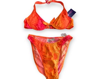 May include: Orange and pink floral print bikini with a halter top and high-waisted bottoms. The bikini top has a bow tie detail in the center. The tag on the bikini top reads "Violet".