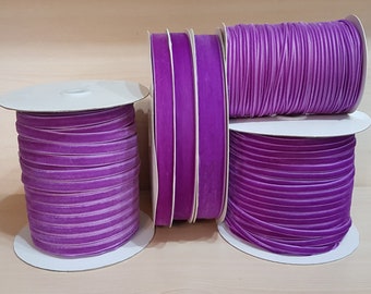 May include: Four spools of purple velvet ribbon, each wound around a white cardboard spool. The ribbon is a deep purple color and has a soft, velvety texture.
