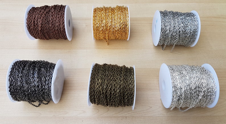 May include: Six spools of chain in different metal finishes: bronze, gold, silver, black, and two shades of copper. The chain is wound around white spools.