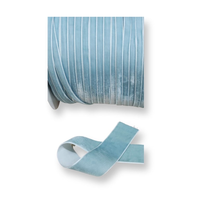K&ouml;nnte beinhalten: Eine Rolle hellblaues Samtband mit plissierter Textur. Ein Abschnitt des Bandes ist abgerollt und zeigt die weiche Textur und Farbe. Das Band eignet sich ideal f&uuml;r Bastelarbeiten, N&auml;hen und Dekorationsprojekte.