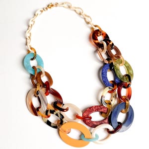 May include: A multi-layered statement necklace featuring large, interlocking oval links in a variety of colors including tortoise shell, solid orange, bright blue, teal, cream, and deep red. The chain is constructed from smooth resin materials.