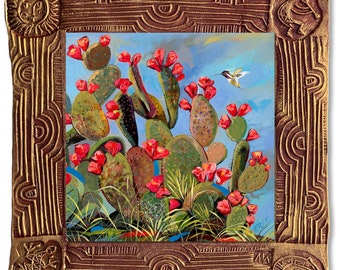 Könnte beinhalten: Ein gerahmtes Gemälde, das einen Kolibri zeigt, der über einem Kaktus mit roten Blüten schwebt. Der Rahmen ist golden mit komplizierten Designs und einer Sonne und einem Vogel auf jeder Seite.