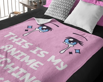 May include: Pink fleece blanket with a white text overlay that reads "This is my anime crying face". The blanket features a cartoon anime eye with blue irises and white eyelashes.