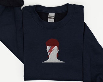 Puede incluir: Sudadera azul marino con una imagen bordada de la cara de David Bowie con un rayo en el ojo. La imagen es en rojo, blanco y azul.