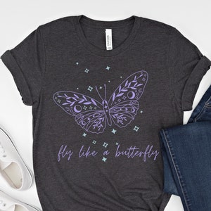 May include: A dark heather grey t-shirt with a purple butterfly design and the text "fly like a butterfly".