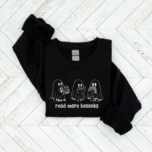 May include: Black sweatshirt with a white graphic of three ghosts reading books. The text "read more booooks" is printed below the ghosts.