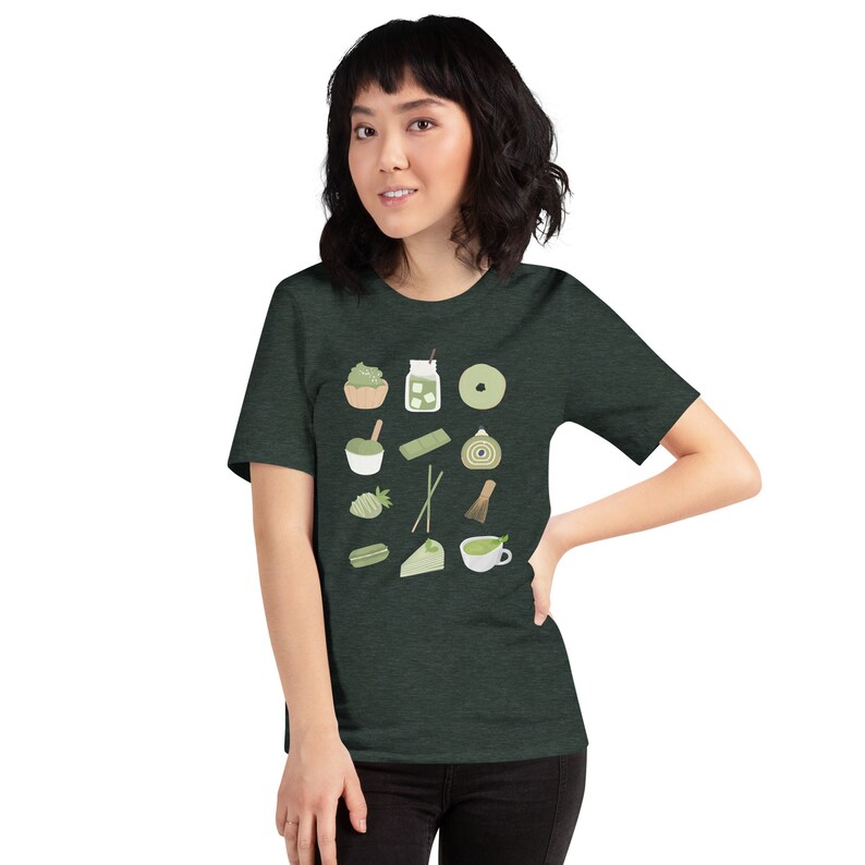 以下が含まれることがあります： 抹茶をテーマにした様々なアイテムが描かれたダークグリーンのTシャツ。抹茶のカップ、抹茶ケーキ、抹茶アイス、抹茶の泡立て器などがあります。