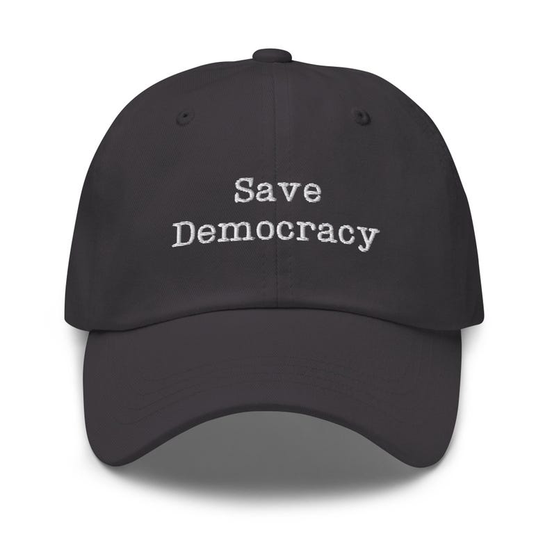 May include: A dark gray baseball cap with the text "Save Democracy" embroidered in white on the front.