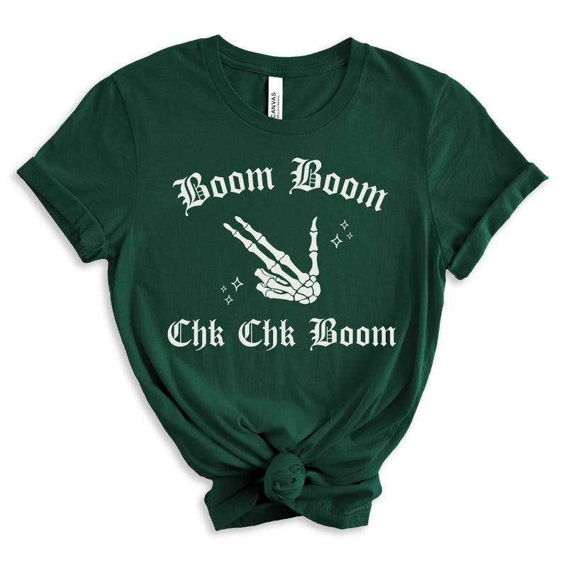 May include: A dark green t-shirt with a white skeleton hand making a peace sign and the text "Boom Boom Chk Chk Boom" in a gothic font.