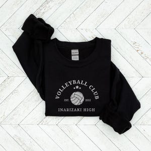 May include: Black sweatshirt with a white embroidered volleyball club logo. The logo says "Volleyball Club" with a volleyball graphic and the text "Est. 2012" and "Inarizaki High".