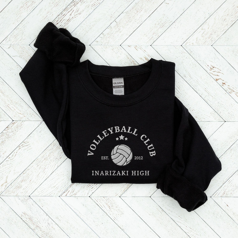 May include: Black sweatshirt with a white embroidered volleyball club logo. The logo says "Volleyball Club" with a volleyball graphic and the text "Est. 2012" and "Inarizaki High".