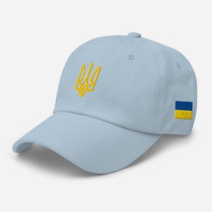 May include: A light blue baseball cap with a yellow embroidered Ukrainian trident and a small Ukrainian flag on the side.