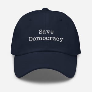 May include: A navy blue baseball cap with white embroidered text that reads "Save Democracy".