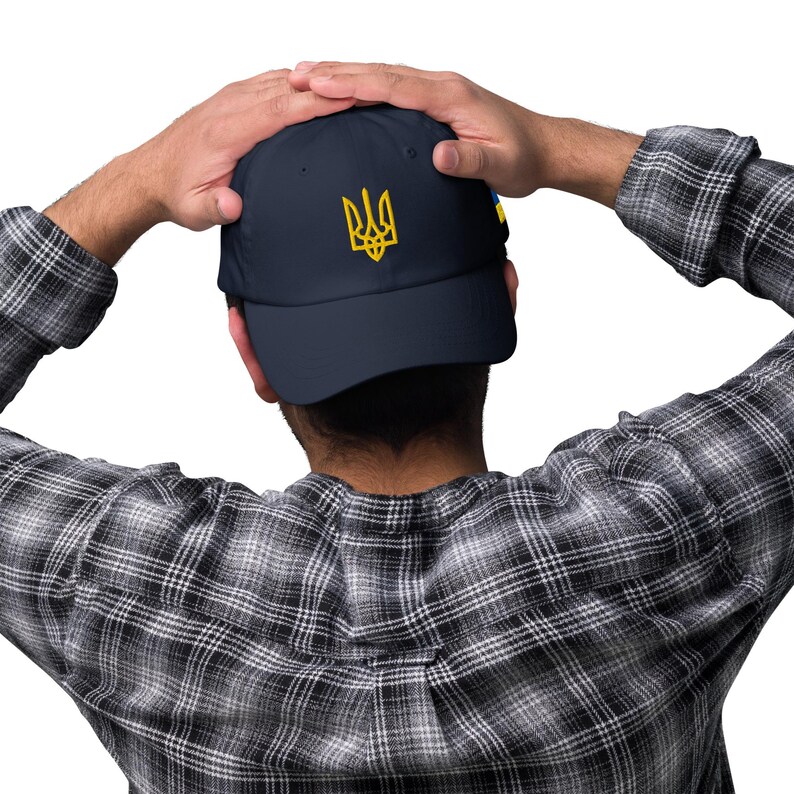 May include: A navy blue baseball cap with a yellow embroidered Ukrainian trident symbol.