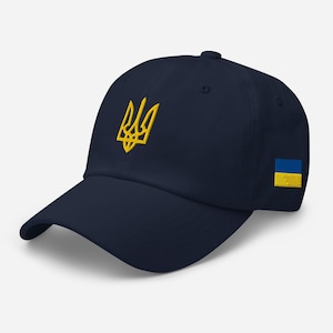 May include: A navy blue baseball cap with a yellow embroidered Ukrainian trident and a small Ukrainian flag patch on the side.