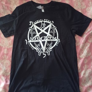 以下が含まれることがあります： 白いペンタグラムのグラフィックが描かれた黒いTシャツ。ペンタグラムには「Samael」と「Lilith」の文字が書かれている。