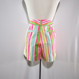 May include: Colorful striped shorts in shades of pink, green, yellow, and blue. The shorts have a high waist and pockets. The vertical stripes create a vibrant and playful look, perfect for warm weather.