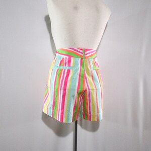 May include: Colorful striped shorts in a variety of bright colors, including pink, green, orange, and blue. The shorts are displayed on a mannequin, showcasing the back view. The shorts have a high waist and pockets.