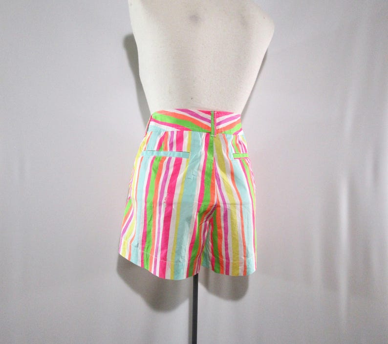 May include: Colorful striped shorts in a variety of bright colors, including pink, green, orange, and blue. The shorts are displayed on a mannequin, showcasing the back view. The shorts have a high waist and pockets.