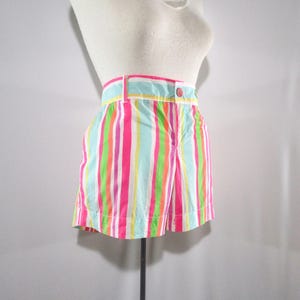 May include: Colorful striped shorts in shades of pink, green, blue, and white. The shorts have a button closure and belt loops. The vertical stripes create a vibrant and playful look, perfect for warm weather.