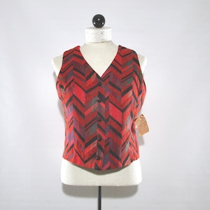 May include: A red, black, and purple chevron patterned vest with a V-neck and button closure. The vest is displayed on a mannequin. A small tag is attached to the side.