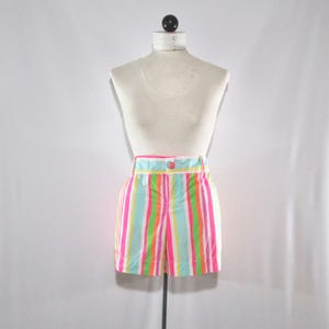 May include: Colorful striped shorts in pink, green, orange, and blue. The shorts have a high waist, a button closure, and pockets. The garment is displayed on a mannequin.