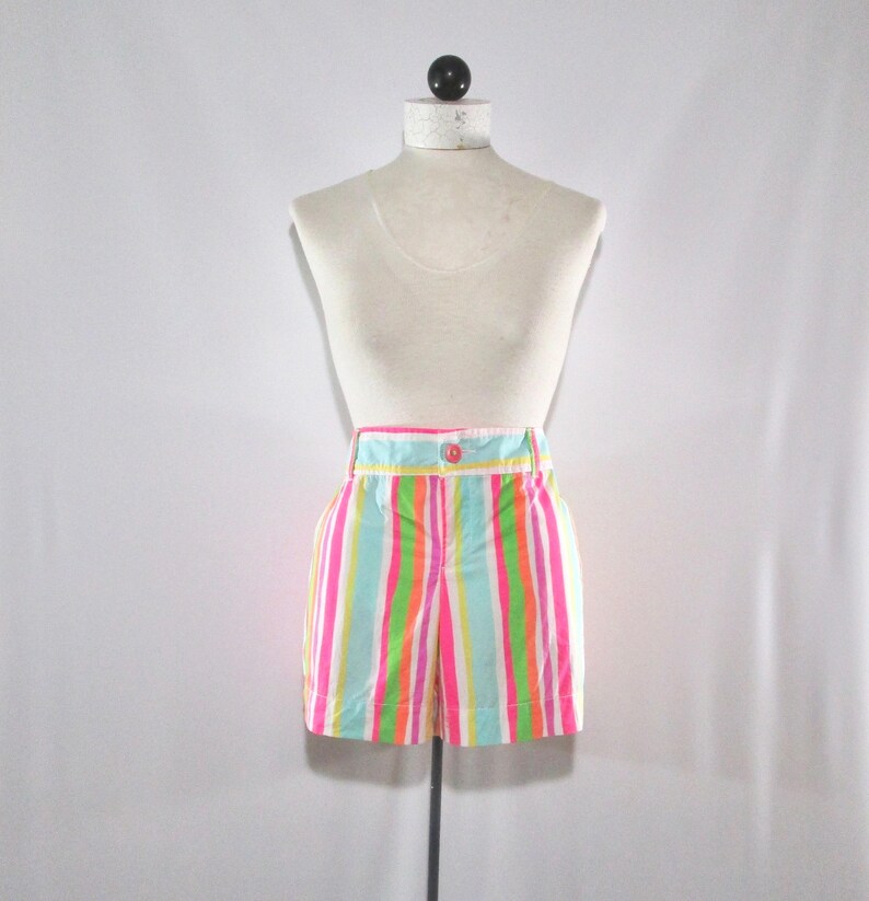 May include: Colorful striped shorts in pink, green, orange, and blue. The shorts have a high waist, a button closure, and pockets. The garment is displayed on a mannequin.