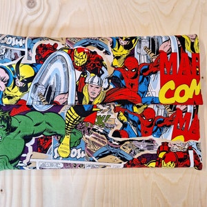 Può includere: Una pochette in tessuto colorata con un collage di personaggi Marvel Comics, tra cui Spider-Man, Hulk, Iron Man e Wolverine. Il tessuto presenta una combinazione di colori rosso, giallo e blu con le parole "Marvel Comics" stampate in giallo.