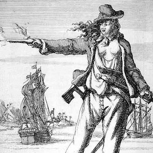 May include: A black and white engraving of a woman pirate holding a pistol in her right hand. She is wearing a hat, a jacket, and pants. She is standing on a shore with a ship in the background.