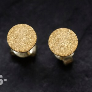 May include: A pair of gold-toned stud earrings with a textured circular design.