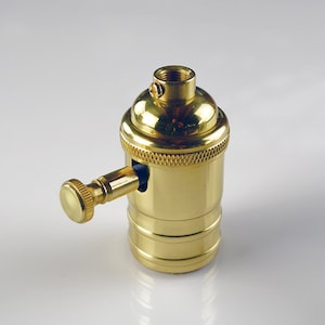 May include: A brass light bulb socket with a side switch. The socket is designed for use with standard light bulbs.