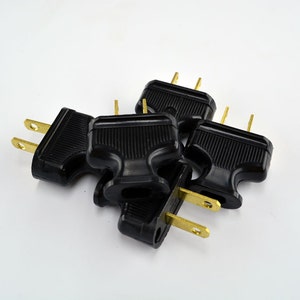May include: Five black electrical outlet adapters with gold-colored prongs. The adapters are stacked on top of each other.