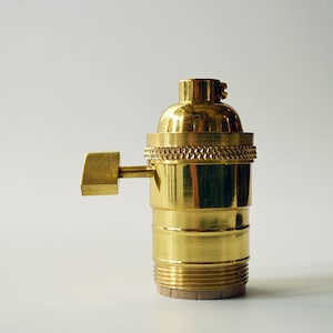 May include: A brass light bulb socket with a side switch. The socket is designed for standard light bulbs.