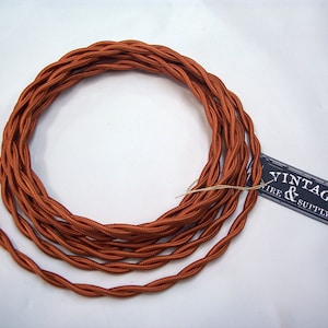 May include: A spool of orange braided electrical cord with a label that reads "Vintage Wire & Supply Co."