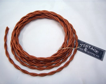 May include: A spool of orange braided electrical cord with a label that reads "Vintage Wire & Supply Co."
