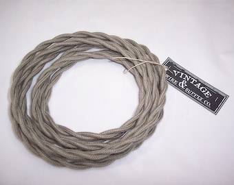 May include: A coil of gray braided electrical cord with a black and white label that reads "Vintage Wire & Supply Co."
