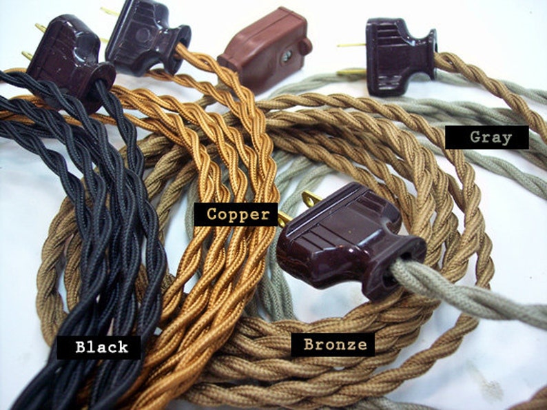May include: Close-up of several electrical cords with plugs in various colors: black, copper, bronze, and gray. The cords are twisted and have a vintage aesthetic. The plugs are brown.