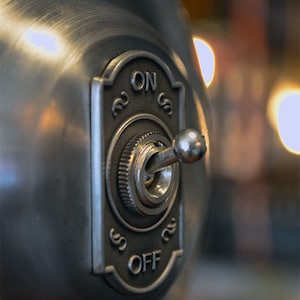 Puede incluir: Un interruptor de luz de metal plateado con un interruptor de palanca y una perilla redonda. El interruptor est&aacute; etiquetado como "ON" y "OFF".