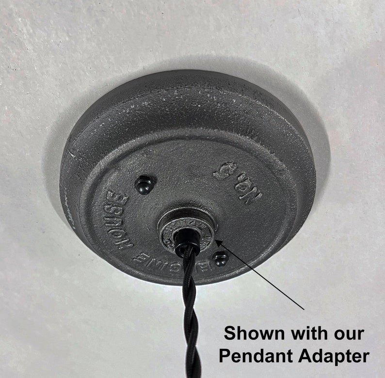 May include: Close-up of a black metal ceiling plate with the text "No. 5" and "HOUSE" visible. A black electrical cord is attached to the plate. Shown with our Pendant Adapter.
