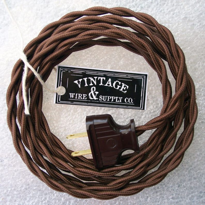 May include: A brown braided electrical cord with a brown two-prong plug. The cord is coiled and has a tag attached that reads "Vintage Wire & Supply Co."