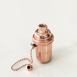 May include: A copper light socket with a pull chain. The socket has a threaded opening for a light bulb and a side switch for turning the light on and off.