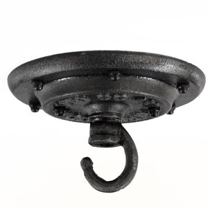 May include: A black, industrial-style ceiling canopy with a hook. The round canopy has a textured surface and is secured with multiple bolts. The hook is curved and designed for hanging items. This fixture is suitable for a variety of lighting and decor applications.