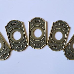 May include: Five antique gold-toned toggle switch covers with the words "ON" and "OFF" engraved on each.