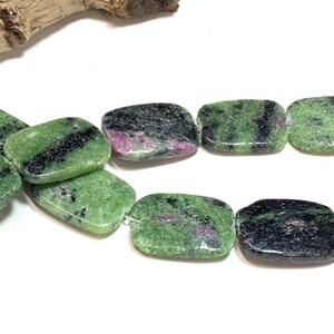 Pu&ograve; includere: Primo piano di una collana di perline rettangolari. Le perline sono un mix di verde, nero e rosa. Il verde &egrave; il colore dominante, con accenti neri e rosa. Le perline sono lisce e lucide, con un aspetto di pietra naturale.