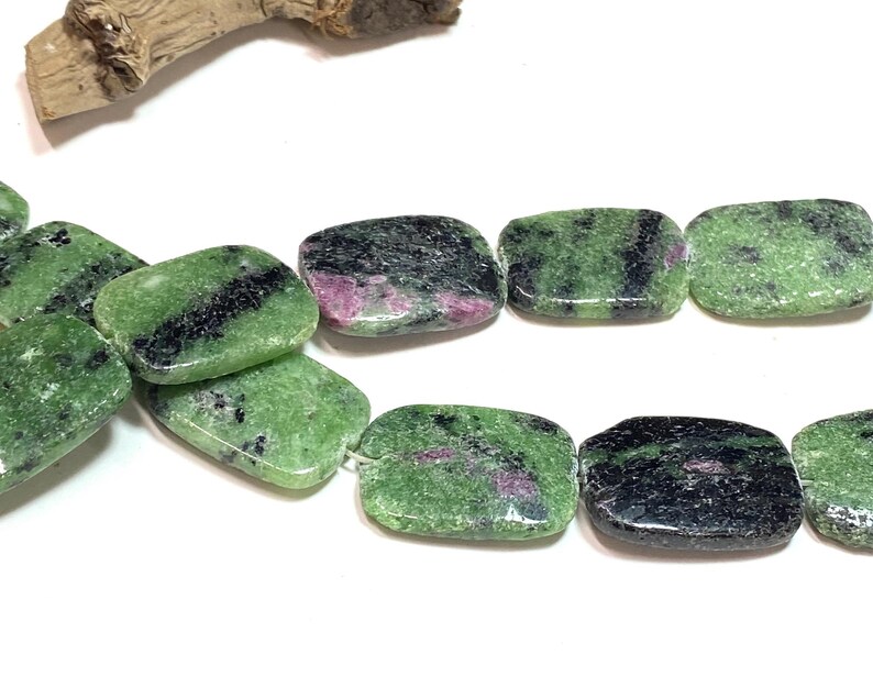 Pu&ograve; includere: Primo piano di una collana di perline rettangolari. Le perline sono un mix di verde, nero e rosa. Il verde &egrave; il colore dominante, con accenti neri e rosa. Le perline sono lisce e lucide, con un aspetto di pietra naturale.