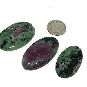 May include: Three oval-shaped green and pink zoisite gemstones. The stones are smooth and polished. The stones are about the size of a US dime.