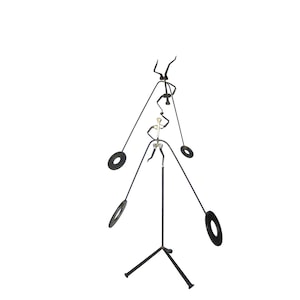 May include: A black metal sculpture of three figures balancing on a tripod stand. The figures are connected by wires and have circular weights attached to them.