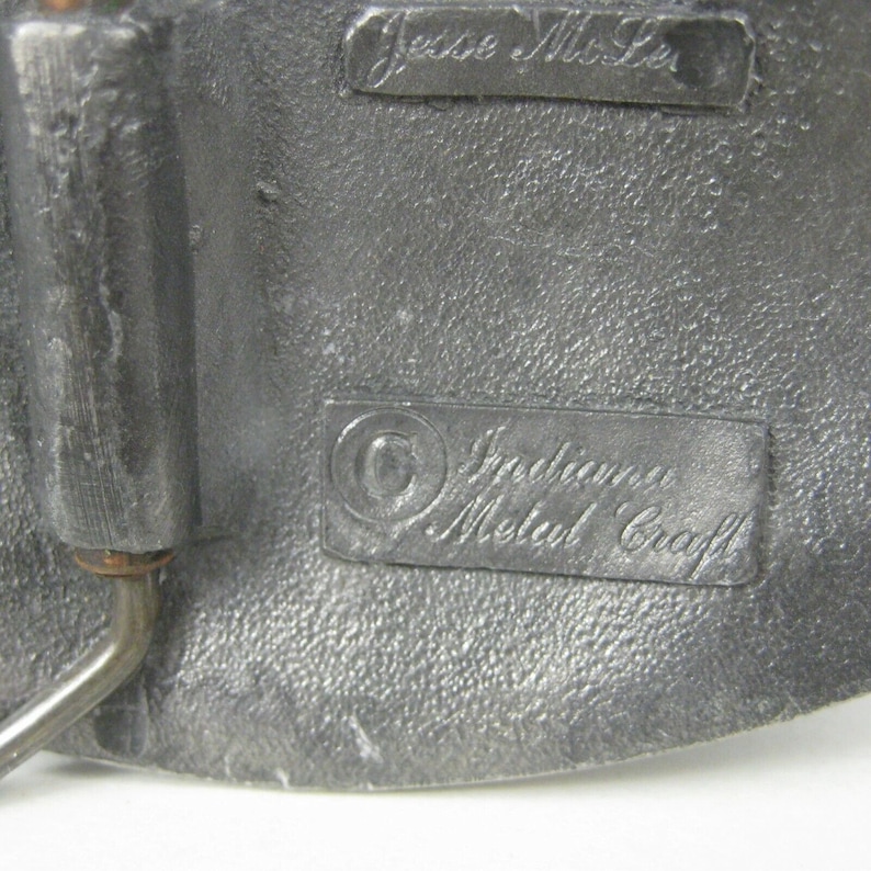 K&ouml;nnte beinhalten: Nahaufnahme einer silbernen G&uuml;rtelschnalle mit dem eingravierten Text "Jesse Moore" und "Indiana Metal Craft".