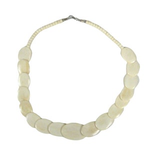 以下が含まれることがあります： 銀色の留め具が付いた、白い楕円形のビーズネックレスです。