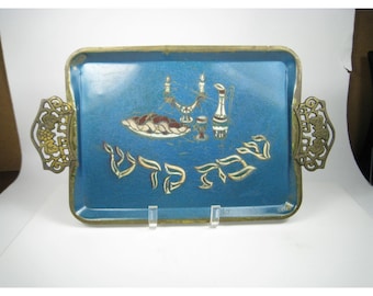May include: A rectangular, turquoise serving tray with gold-colored handles and trim. The tray features gold-colored illustrations of a menorah, a pitcher, and text. The handles have an ornate, openwork design.